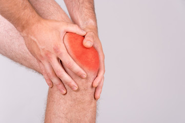 Man with knee pain over grey background