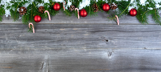Fototapeta na wymiar snow covered Christmas fir tree branches with seasonal decorations on weathered wood for holiday concept