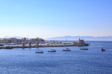 Windmills and st nicholas tower and lighthouse in Mandraki port in Rhodes, Dodecanese, Greece