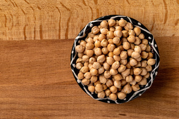 Bowl of chickpeas at wooden board. Top view, arranged at right centre.