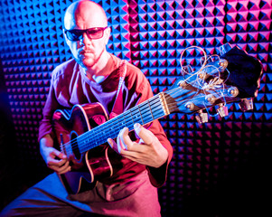 Obraz premium Young man playing on the acoustic guitar in sound recording studio.