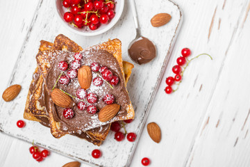 stack of fried toast with chocolate cream, red currant and almonds