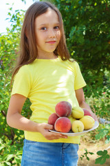 brunette cute girl holding peaches and apricots in her hands