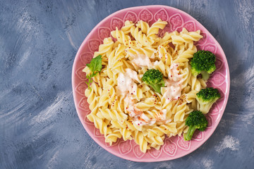 Spiral pasta with broccoli on a gray background. Top view, copy space. Flat lay.