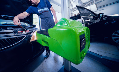 Worker checks and adjusts the headlights of a car's lighting system