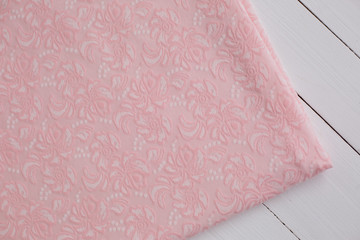 the fabric is a knit viscose pink color. fabric on white wooden background. fabric with pattern