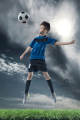 Obraz na płótnie Canvas football player hitting the ball with head on a soccer stadium