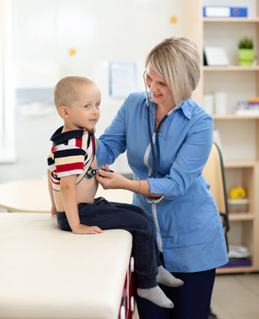Doctor examining boy using stethoscope