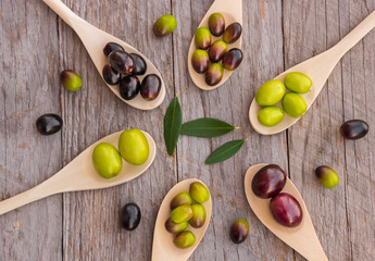 Different types of olives on wooden spoons