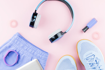 Woman sneakers, headphones, fitness tracker and smartphone on pastel pink background. Sport fashion concept. Flat lay