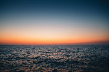 An orange blue sunrise sky, a dawn above a sea water, sunset background