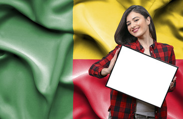 Woman holding blank board against national flag of Benin