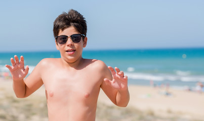 Young child on holidays at the beach scared in shock with a surprise face, afraid and excited with...