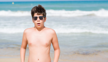 Young child on holidays at the beach scared in shock with a surprise face, afraid and excited with...