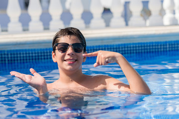 Young child on holiday at the swimming pool by the beach very happy pointing with hand and finger