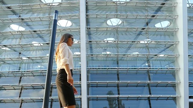 Successful business woman walking near the business centre, dizzing around herself.