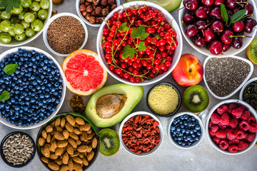 Table with healthy food assortment, fruit, nuts, seeds and various berries, superfoods selection, vegan diet concept