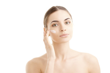 Woman applying cream onto her face at isolated white background