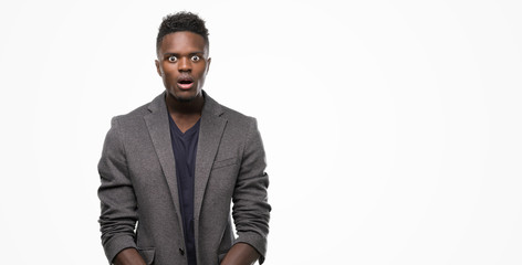 Young african american man wearing a jacket scared in shock with a surprise face, afraid and...