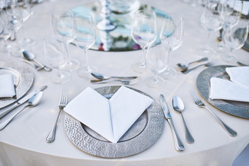 Dinner table setting with stainless plate, fork, spoon and napkin with water glasses in closeup