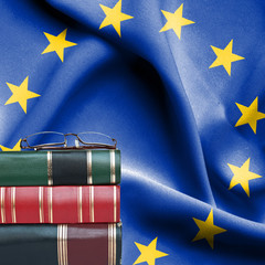 Education concept - Stack of books and reading glasses against National flag of European Union