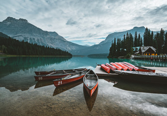 Red kayaks dry upside down. Emerald Lake in Canadian Rockies with mountains and trees and...