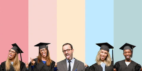 Obraz premium Senior teacher with his graduate students looking at camera showing tongue and making victory sign with fingers