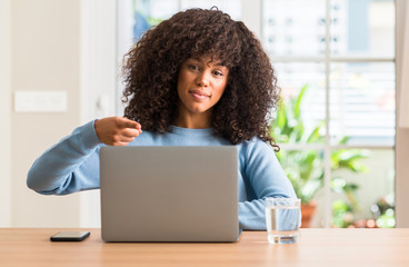 African american woman using laptop computer at home very happy pointing with hand and finger