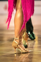 Beautiful womanish and masculine legs in active ballroom dance, indoors