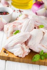 Raw chicken wings on a cutting board. Ingredients for cooking, spices, onion and garlic
