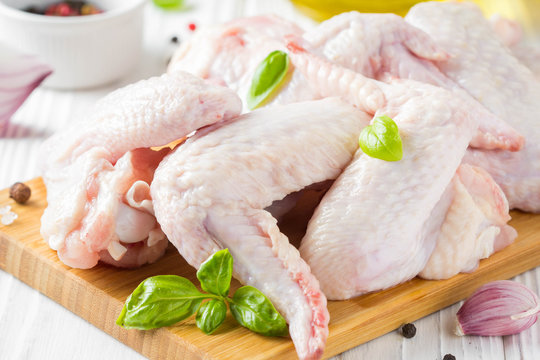 Raw chicken wings on a cutting board. Ingredients for cooking, spices, onion and garlic