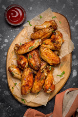 Grilled chicken wings with ketchup and mustard sauces on wooden board. Traditional baked bbq buffalo