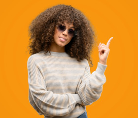 African american woman wearing a stripes sweater very happy pointing with hand and finger to the...