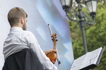 Young man with a violin in the park
