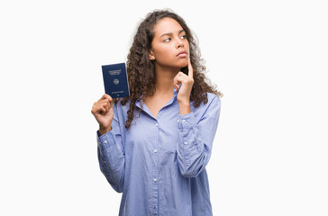 Young hispanic woman holding passport of Germany serious face thinking about question, very confused idea - obrazy, fototapety, plakaty