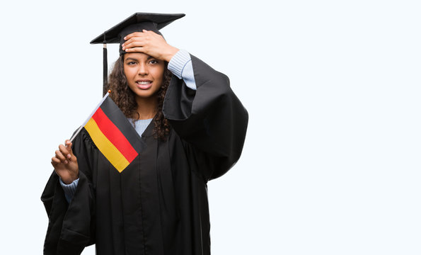 Young hispanic woman wearing graduation uniform holding flag of Germany stressed with hand on head, shocked with shame and surprise face, angry and frustrated. Fear and upset for mistake.