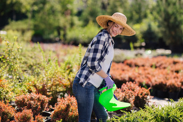 Young female gardener watering the plants in garden