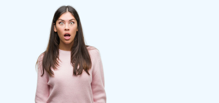 Young beautiful hispanic woman wearing a sweater afraid and shocked with surprise expression, fear and excited face.