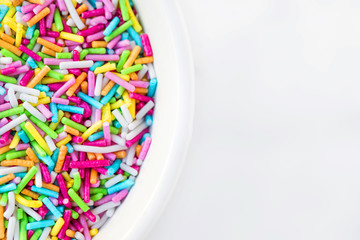 Fototapeta premium Sugar sprinkles in a bowl on a white background as decoration for cake and bakery. Top view
