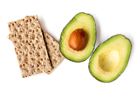 Isolated avocado fruit. Two halves of avocadoes with wholegrain crispy bread  isolated on white background. Healthy breakfast with Crispbread