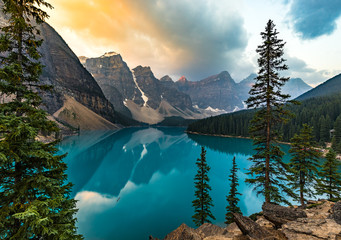 Sunrise with turquoise waters of the Moraine lake with sin lit rocky mountains in Banff National Park of Canada in Valley of the ten peaks.