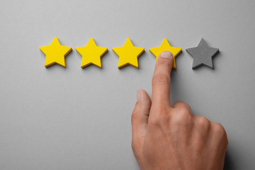Four golden yellow stars out of five. Man points finger at the star, puts rating