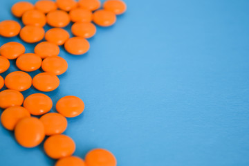 A pile of orange pills on a blue background