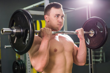 Fototapeta na wymiar Muscular young man lifting weights in gym