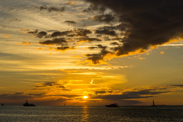 Naklejka na ściany i meble USA, Florida, Dramatic orange sky sunset with some boats on the ocean water