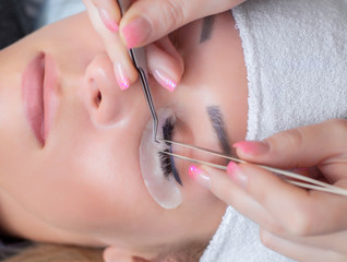 Naklejka premium Beautiful Woman with long eyelashes in a beauty salon. Eyelash extension procedure. Lashes close up