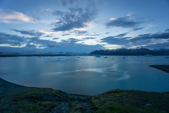 Iceland - Coast of glacier lagoon joekulsarlon with floating ice floes at midnight