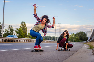 Skateboard girls riding long-boards down the road