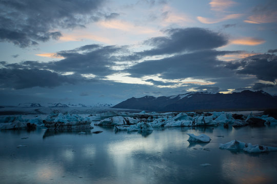 Iceland - Reflecting clouds in glacier lagoon between huge ice blocks