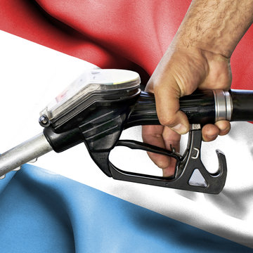 Gasoline consumption concept - Hand holding hose against flag of Luxwmbourg